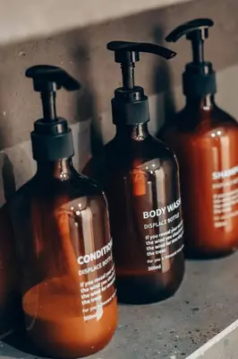 a group of four bottles of soap on a shelf at 4 guests apartment near Glyfada center in Athens