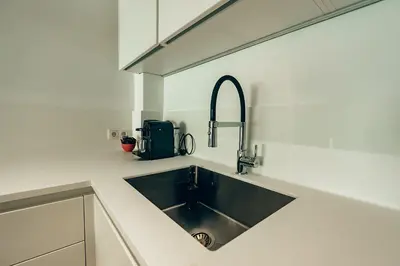 a kitchen with a sink in a white kitchen at 4 guests apartment near Glyfada center in Athens