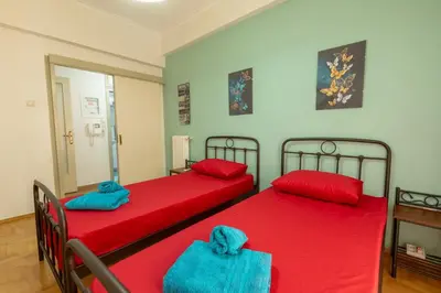 two beds in a room with red sheets and blue towels at Athens center traditional & classic 2BR apartment in Mesochórion