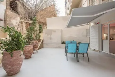 a patio with two chairs and a table and potted plants at The Courtyard Oasis in Athens
