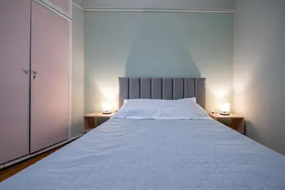 a bedroom with a large white bed with two lamps at Athenian Getaway near Metro-Agios Nikolaos by ΜΡS in Athens