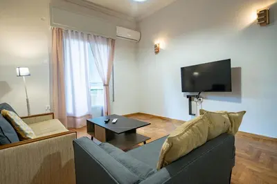 a living room with a couch and a tv at Athenian Getaway near Metro-Agios Nikolaos by ΜΡS in Athens