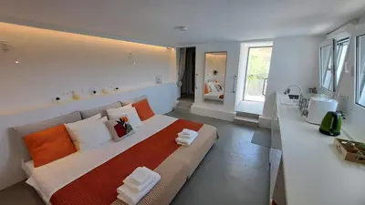 a bedroom with a large bed with orange and white pillows at Anemelia & Helios Studio in Anavissos