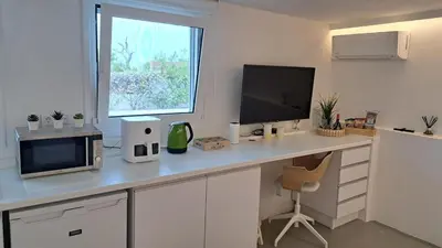 a white desk with a microwave and a television at Anemelia & Helios Studio in Anavissos