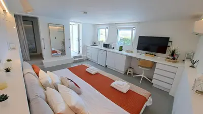 a large living room with a couch and a television at Anemelia & Helios Studio in Anavissos