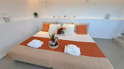 a bedroom with a large bed with orange and white pillows at Anemelia & Helios Studio in Anavissos