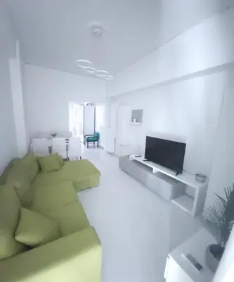 a living room with a green couch and a television at Elegant-Quiet 2' Metro Center in Athens