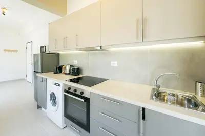 a kitchen with white cabinets and a sink and a dishwasher at Urban Apartment on Top with View in Athens