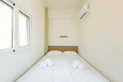 a white bed in a white room with two pillows at Urban Apartment on Top with View in Athens