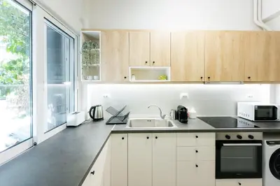a kitchen with white cabinets and a large window at My Athens Home near Metro Station in Athens