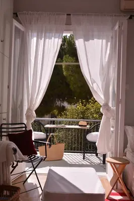 a balcony with white curtains and a table and chairs at Detached House 4km away from Acropolis & Riviera in Athens