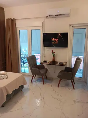 a bedroom with a desk and two chairs and a tv at PARTHENON In HORIZON in Athens