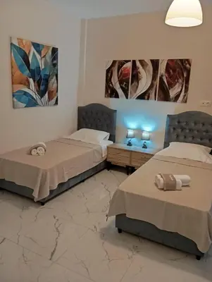 two beds in a room with paintings on the wall at PARTHENON In HORIZON in Athens