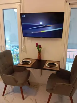 a desk with two chairs and a television on a wall at PARTHENON In HORIZON in Athens