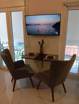 a living room with a table and two chairs and a television at PARTHENON In HORIZON in Athens