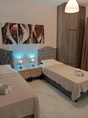 two beds in a room with two tables and two lamps at PARTHENON In HORIZON in Athens