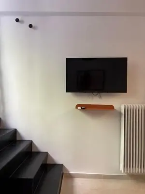 a flat screen tv on a wall with a radiator at Relax adobe in central Athens in Athens
