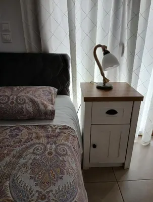 a lamp on a night stand next to a bed at Akrivis studio in Athens