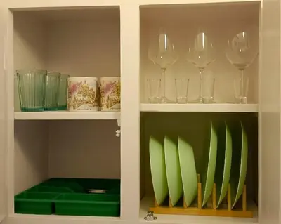 two shelves filled with wine glasses and green chairs at A room with a view in Athens