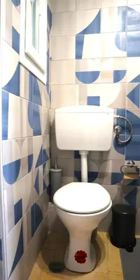 a bathroom with a toilet and blue and white tiles at A room with a view in Athens