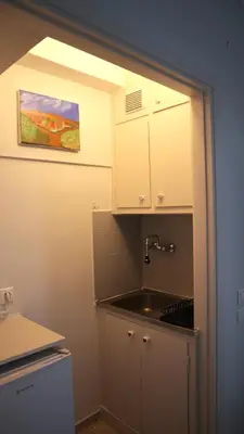 a kitchen with a sink and white cabinets and a painting at A room with a view in Athens