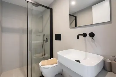 a white bathroom with a sink and a shower at LIV - Deluxe 2BD Apartment in Athens in Athens