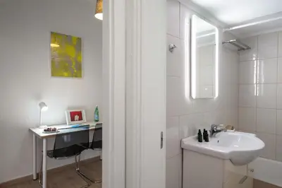 a white bathroom with a sink and a desk at Encrin Apartment by LobbySquare in Athens