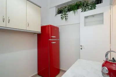 a red refrigerator in a kitchen with white cabinets at Encrin Apartment by LobbySquare in Athens
