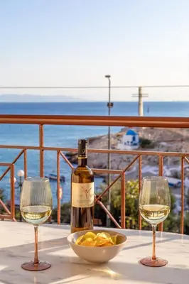 a bottle of wine and two wine glasses on a table at Sunny Seaside Cozy Home in Piraeus