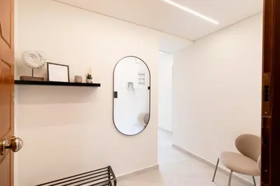a hallway with a mirror and a chair at Sunny Seaside Cozy Home in Piraeus