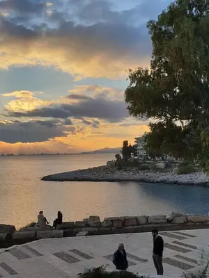 a group of people sitting by the water at sunset at Sunny Seaside Cozy Home in Piraeus