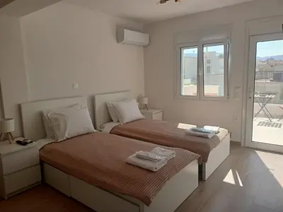 a white bedroom with two beds and a window at IVory Suites near Athens Airport in Spáta