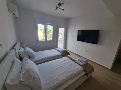 a white bedroom with a bed and a television at IVory Suites near Athens Airport in Spáta
