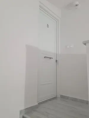 a white door with a metal handle in a room at IVory Suites near Athens Airport in Spáta