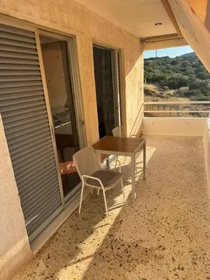 a table and chairs on the balcony of a house at Aggelakos Rooms in Porto Rafti