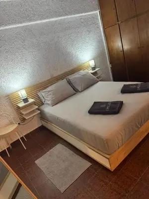 a bedroom with a large bed with a wooden headboard at Aggelakos Rooms in Porto Rafti