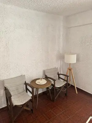 a room with a table and chairs and a lamp at Aggelakos Rooms in Porto Rafti
