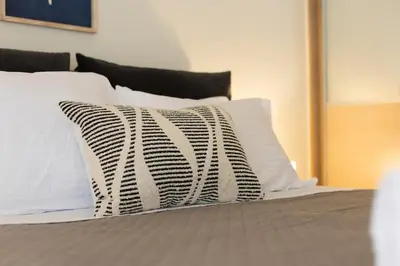 a bed with white pillows and a black and white pillow at Beach & City - Glyfada 2BR in Athens