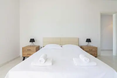 a bedroom with a large white bed with two night stands at Villa Svoronou Athens Riviera in Áyios Nikólaos