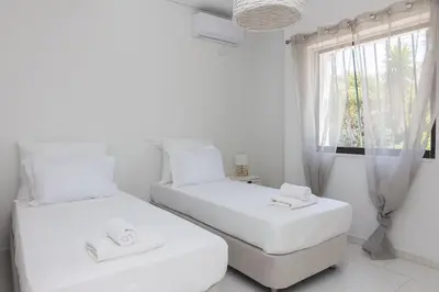 two beds in a white room with a window at Villa Svoronou Athens Riviera in Áyios Nikólaos