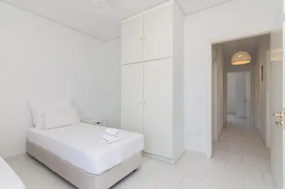 a white bedroom with a white bed and a hallway at Villa Svoronou Athens Riviera in Áyios Nikólaos