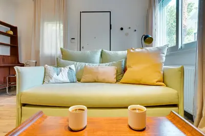 a yellow couch in a living room with a table at Garden Level Gem in the City in Athens