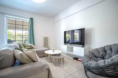 a living room with a couch and a tv and a table at Barbara's sweet home Glyfada by ΜΡS in Athens