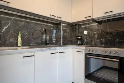 a kitchen with white cabinets and a sink and an oven at Barbara's sweet home Glyfada by ΜΡS in Athens