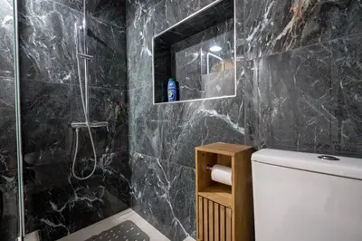 a bathroom with black marble walls and a toilet at Barbara's sweet home Glyfada by ΜΡS in Athens