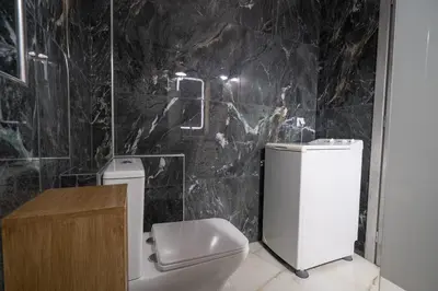a bathroom with a toilet and a black marble wall at Barbara's sweet home Glyfada by ΜΡS in Athens