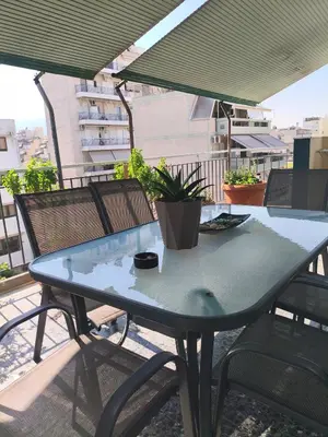 a blue table and chairs on a balcony with an umbrella at Sofia's Beauty apartments in Athens