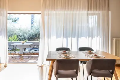 a dining room with a table and chairs and a large window at Spacious 3-Bedroom Getaway with Balcony in Glyfada in Athens