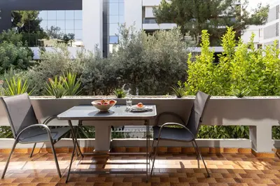 a table and chairs on a balcony with plants at Spacious 3-Bedroom Getaway with Balcony in Glyfada in Athens