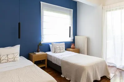 two beds in a room with blue walls at Spacious 3-Bedroom Getaway with Balcony in Glyfada in Athens